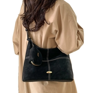 Black suede shoulder bag with contrast stitching and mini pouch on white background
