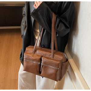 Detail of vintage brown leather underarm bag featuring dual front zipper pockets