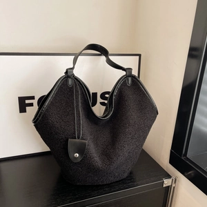 Detail of black faux fur shoulder bag with leather trim and metallic buckle hardware