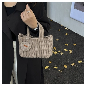 Detail of handmade khaki knit bag featuring heart charm and leather hand-made label