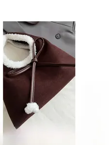 Détail d'un sac porté épaule en daim avec bordure en fausse fourrure et nœud élégant