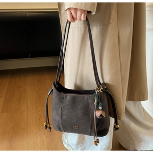 Detail of dark brown leather underarm bag with drawstring and golden flower pendant