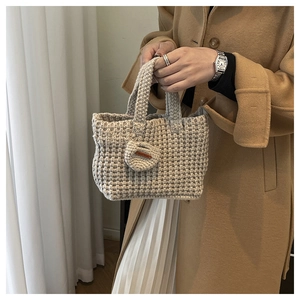 Detail of oat beige crochet woven bag with 'Hand Made' leather tag and round charm