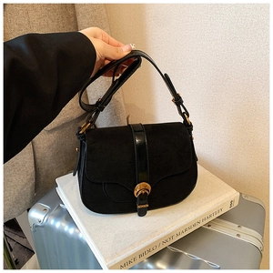 Detail of vintage black saddle bag featuring matte suede and polished leather contrast