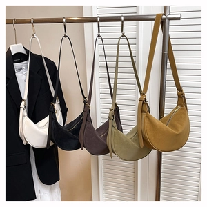 Five minimalist crescent shoulder bags in various colors hanging on a retail rack