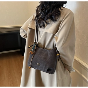 Detail of dark brown vintage hobo bag with tassel and bead charms on model