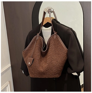 Detail of brown plush tote bag with faux leather trim hanging over a black blazer