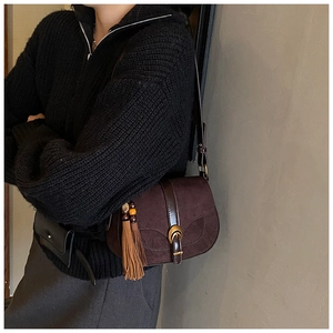 Detailed macro view of dark brown saddle bag with retro metal buckle and tassel decoration