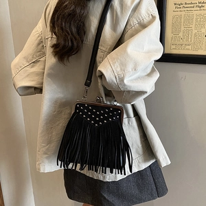 Detail of black leather crossbody bag featuring tiered tassels and silver stud accents