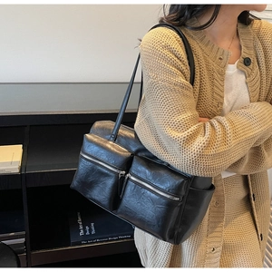Detail of minimalist black faux leather tote bag with functional zipper pockets