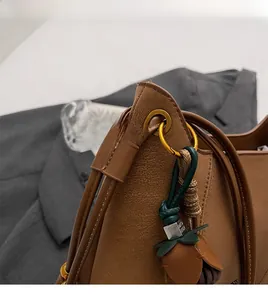 Detail of brown pebbled leather texture with gold hardware and green tassel charm