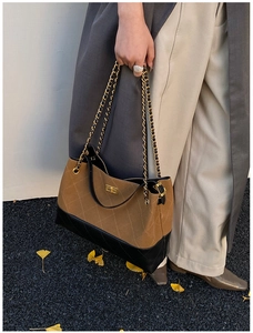 Detail of quilted two-tone chain bag featuring brown suede and black leather texture