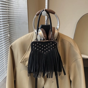 Detailed view of black suede crossbody bag with silver studs and long fringe tassels