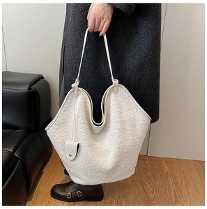 Detail of creamy sherpa tote bag featuring premium leather trim and large capacity