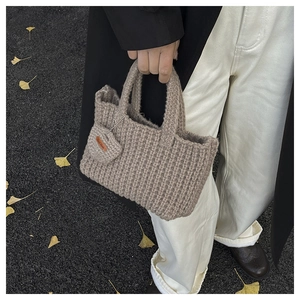 Detailed close-up of handmade oatmeal knitted tote bag with woven rib texture and label