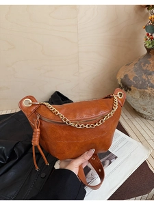 Détail du sac banane en similicuir marron avec chaîne dorée et gland de fermeture éclair