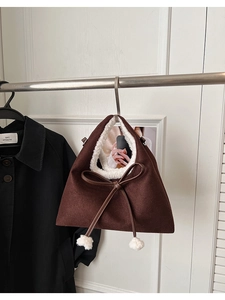 Détail d'un sac à bandoulière en suède avec un grand nœud et des boules en peluche blanches