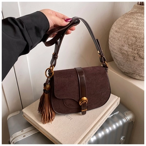 Detail of vintage dark brown saddle bag with suede stitching and long leather tassels