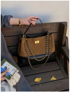 Detail of color-block tote featuring brown suede, black leather, and gold chain strap