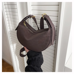 Detail of vintage coffee crescent bag with matte texture and golden zipper accents