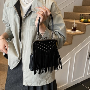 Detail of black vintage leather handbag with fringe, silver rivets and metal frame clasp