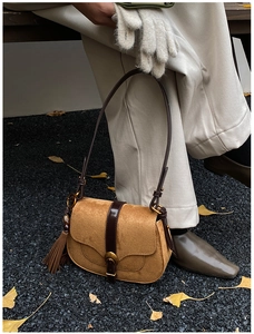 Detail of caramel suede saddle bag with vintage metal buckle and leather fringe tassel