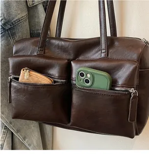 Detail of deep brown shoulder bag showing two front zipper pockets for phone and wallet storage