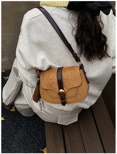 Detail of vintage saddle bag in ginger suede with dark brown leather strap and tassel decoration