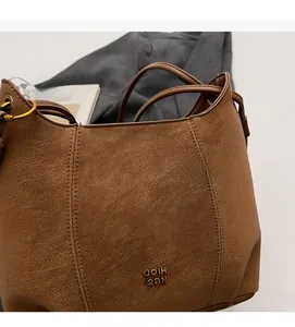 Close-up of brown vintage shoulder bag showing faux leather texture and gold hardware details