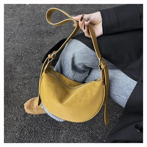 Detail of a ginger yellow crescent bag with textured faux leather and adjustable strap