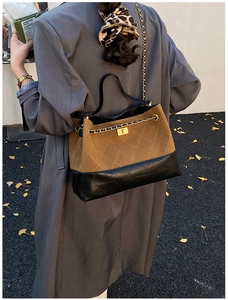Brown suede crossbody bag with gold chain strap worn by a model in a winter coat