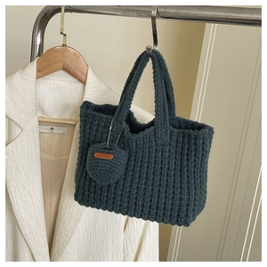 Detailed knit texture of dark blue handmade crochet handbag with a heart charm