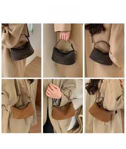 Detail view of suede underarm bag showing matte gold hardware and textured finish