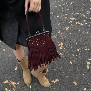 Detail of wine red suede handbag with silver studs and long fringe tassels