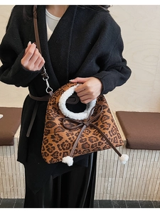 Détail du sac en daim léopard avec poignée en fausse fourrure et pompons blancs