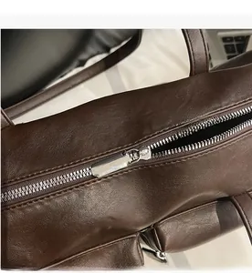 Macro shot of smooth silver metal zipper on a dark brown textured leather shoulder bag