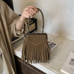 Close-up of bohemian suede handbag with vintage metal studs and long fringe details