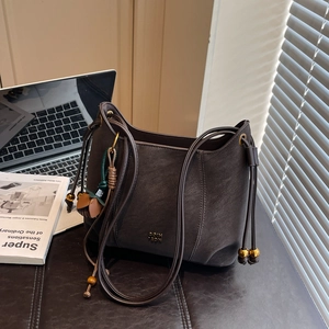 Detail of dark brown faux leather tote bag with gold beads and a magazine setup