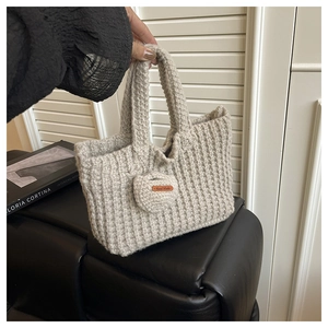 Detail of hand-knitted cotton tote bag with a round tag featuring a Hand Made leather label