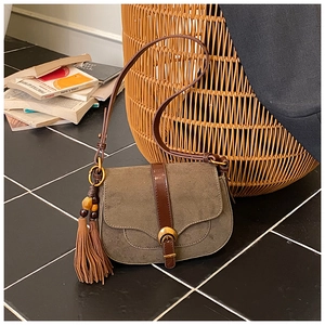 Detail of vintage suede saddle bag with fringe tassel and metallic crescent buckle
