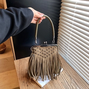 Detail of olive green fringe handbag featuring retro metal rivets and clasp closure