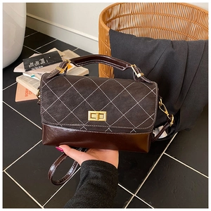 Detail of dark brown quilted leather handbag with gold clasp and white stitching