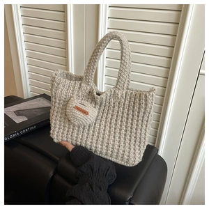 Macro detail of hand-knitted gray tote bag featuring textured vertical stripes and heart charm