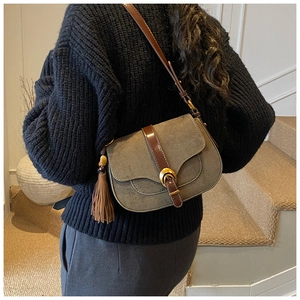 Side view of a vintage sage green saddle bag with brown leather trim worn by a model