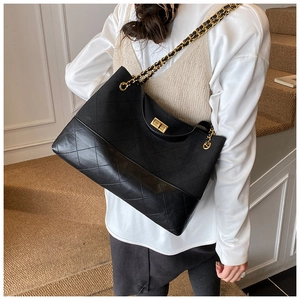 Detail of quilted leather and canvas bag featuring a golden chain strap and twist-lock