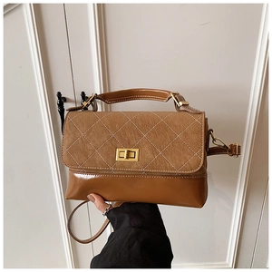 Detail of retro rhombus pattern and gold twist lock on brown leather shoulder bag