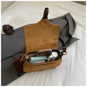 Detailed interior view of tan suede saddle bag showing storage for phone and lipstick