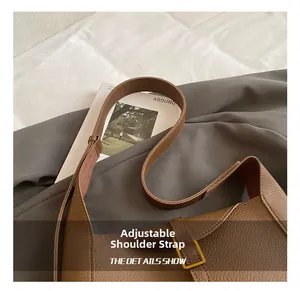 Détails de la bandoulière réglable en cuir marron motif litchi avec boucle dorée mate