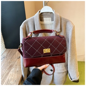 Detail of burgundy quilted crossbody bag featuring gold twist lock and dual texture leather