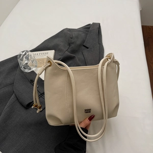 Detail of beige hobo bag with dual cord straps and decorative gold metal beads
